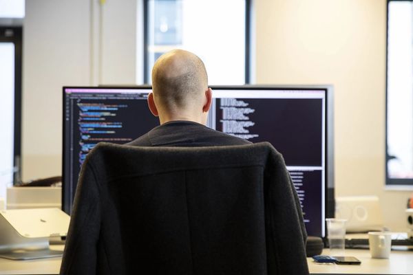 Collega aan het werk met code op twee schermen